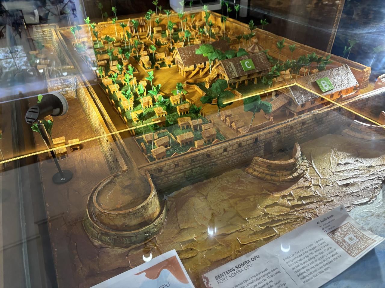 Sebuah diorama miniatur terperinci dari Benteng Somba Opu, memperlihatkan tembok bentengnya, gerbangnya, dan rumah-rumah tradisionalnya.
