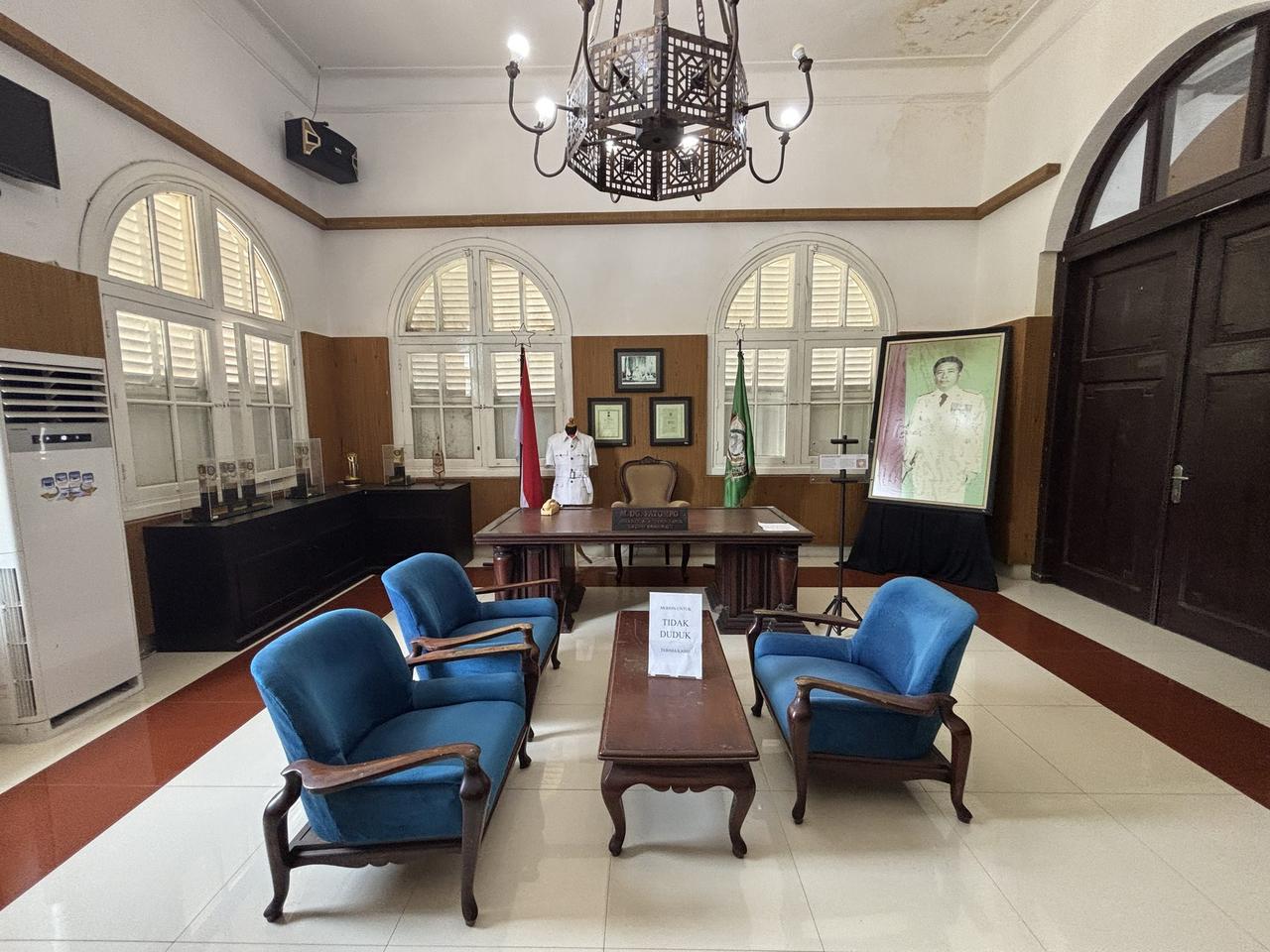 Sebuah kantor wali kota yang dipertahankan keasliannya, dengan meja kayu, kursi berlengan biru, lampu gantung, dan sebuah potret di dinding, ditandai dengan papan nama M. Dg. Patompo.
