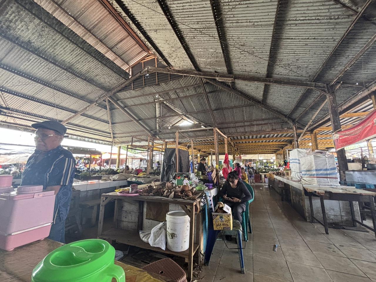 Bagian pasar yang lebih tenang, para pedagang duduk di antara karung dan keranjang, menunggu pembeli.