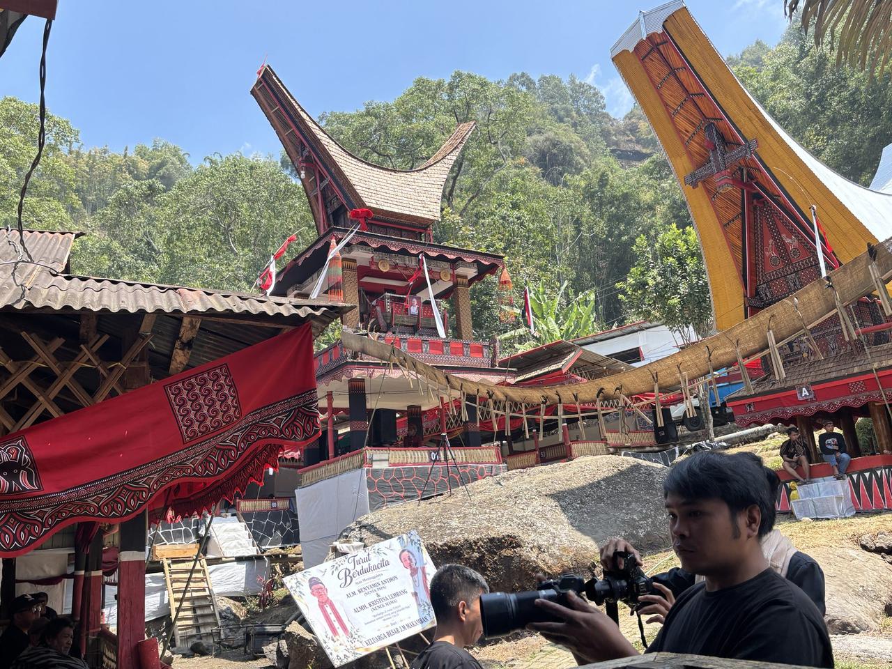 The two-story Lakian building decorated with red banners, a condolence signboard with photographs standing in front of it.