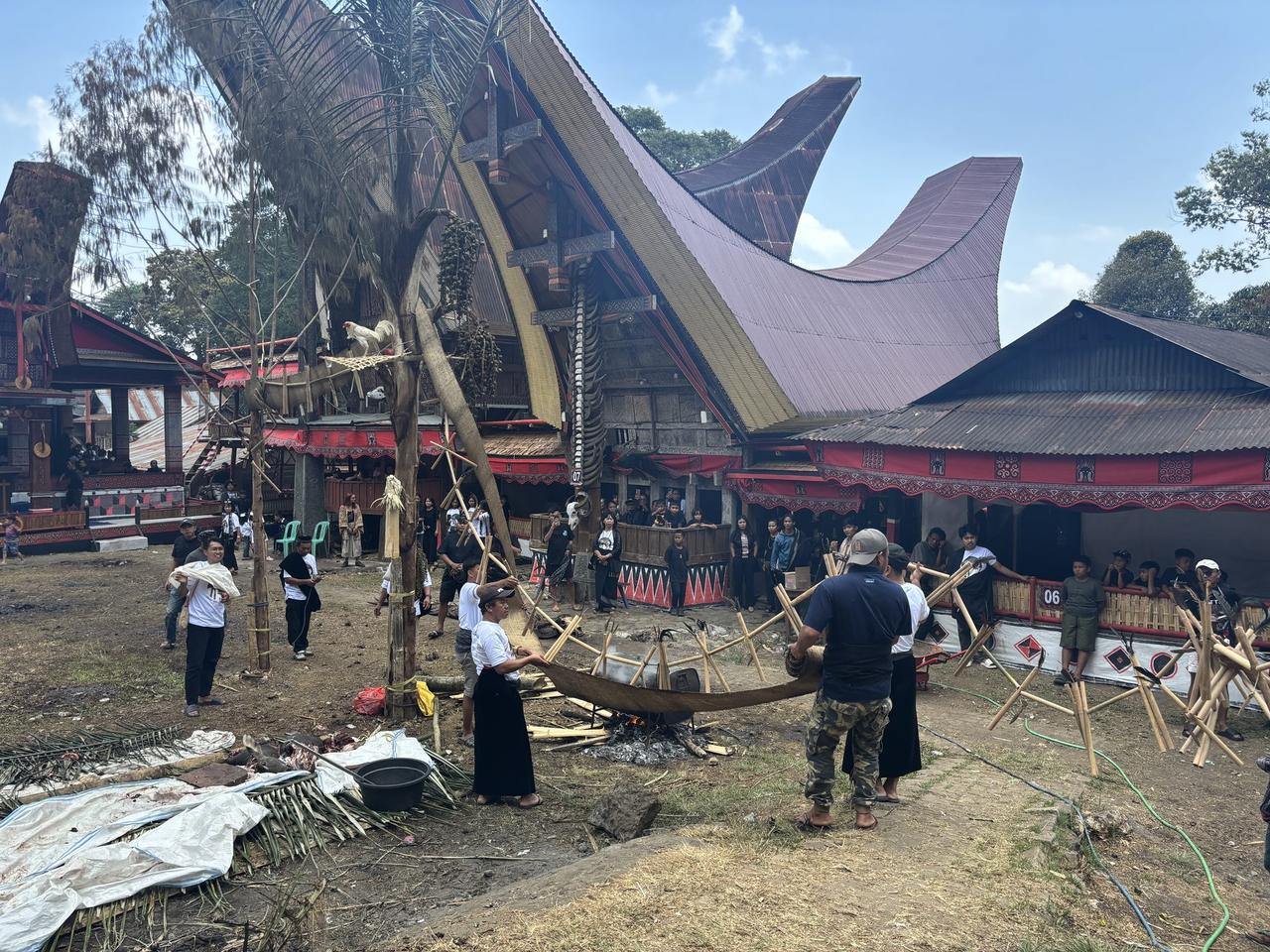 Men working a long curved piece of wood over an open fire, bending it by hand.