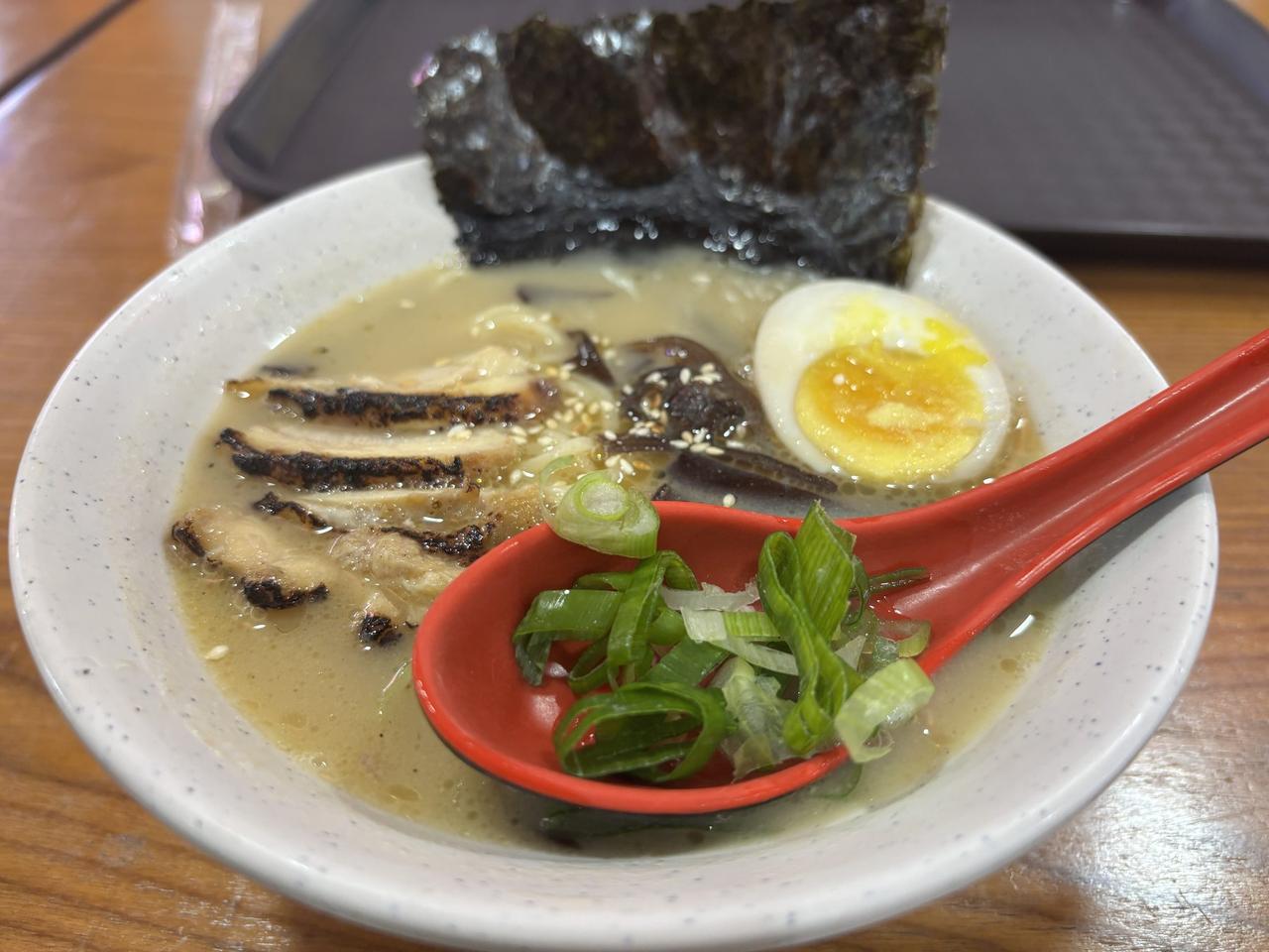 A bowl of Original Tsuka Ramen with sliced chashu, a soft-boiled egg, nori, and scallions in a creamy broth.