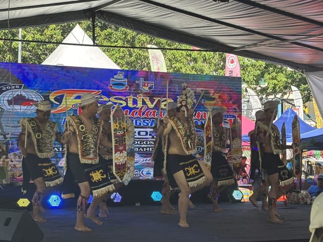 Dancers in traditional dress performing with swords and shields at a local festival.